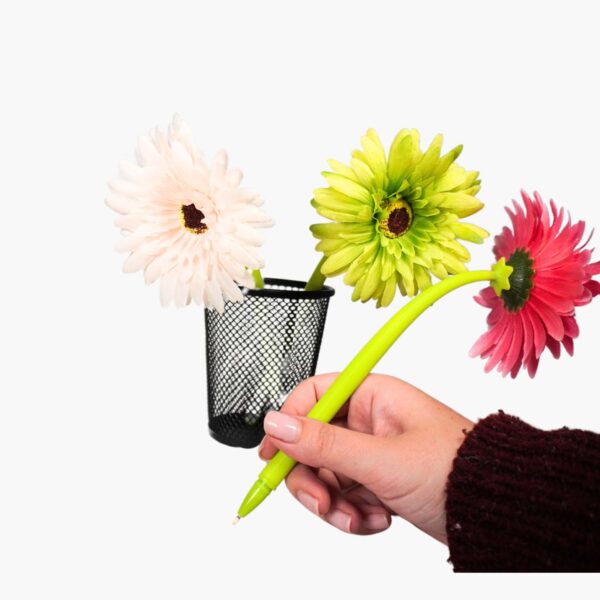 Hand holding a Gerber flower pen, ready to write, with additional pens blurred in the background