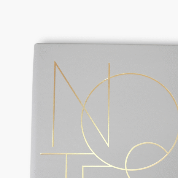 Close-up of gold foil NOTES lettering on grey luxury notebook