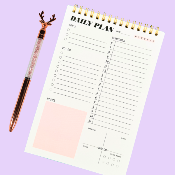 Pink A5 daily planner notepad ring-bound with sections for date, top 3 priorities, to-do, notes, schedule, meal planner, and water intake